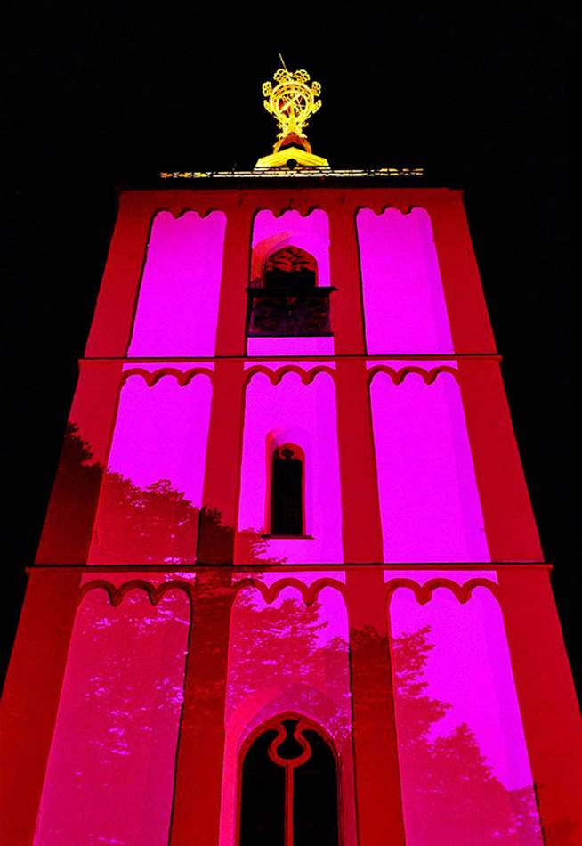 Turm der Nikolaikirche Siegen bei Nacht in Magenta illuminiert, mit vergoldetem Krönchen